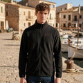 Mann in schwarzer Majovida Fleecejacke mit orangem Stick am Hafen auf Mallorca